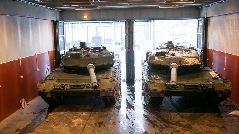 To stridsvogner sett forfra parkert inne i en hall