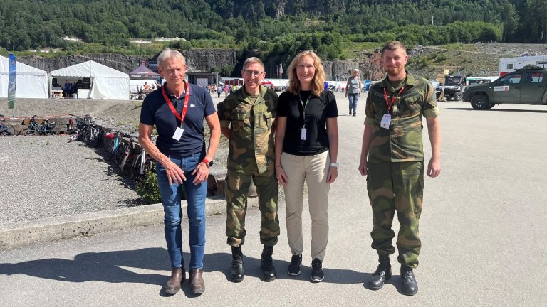 To militære, en sivil og direktør Gro Jære avbildet på skytterstevne