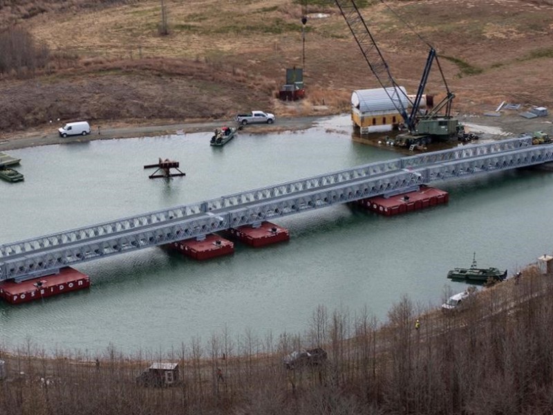 Tung taktisk bro utplasseres med kran over vann, sett fra luften