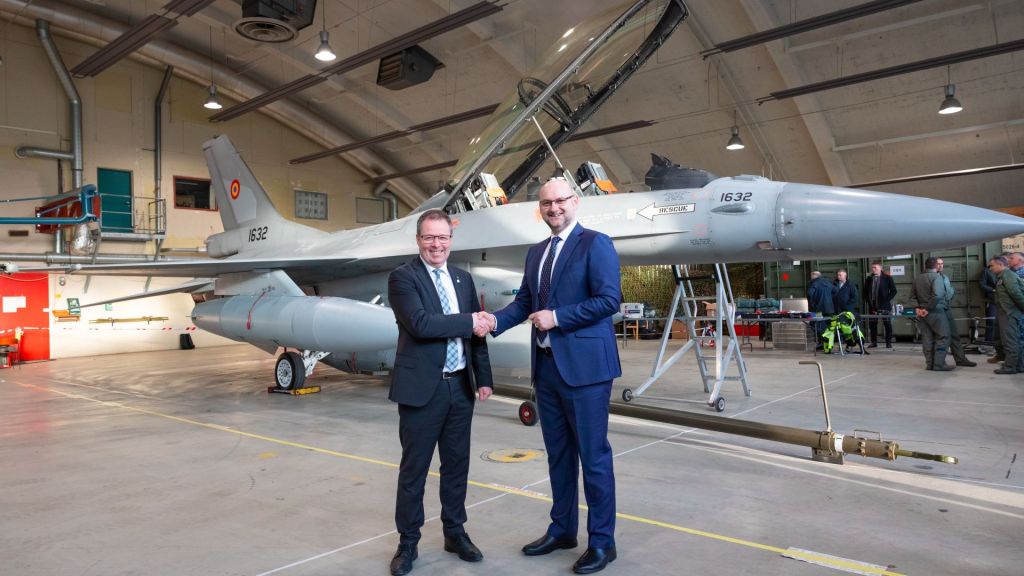 Her tar forsvarsminister Bjørn Arild Gram og Romanias ambassadør Cristian Bădescu hverandre i hendene foran ett av de første F-16-flyene som skal til  Romania. Foto: Onar Digernes Aase / Forsvaret