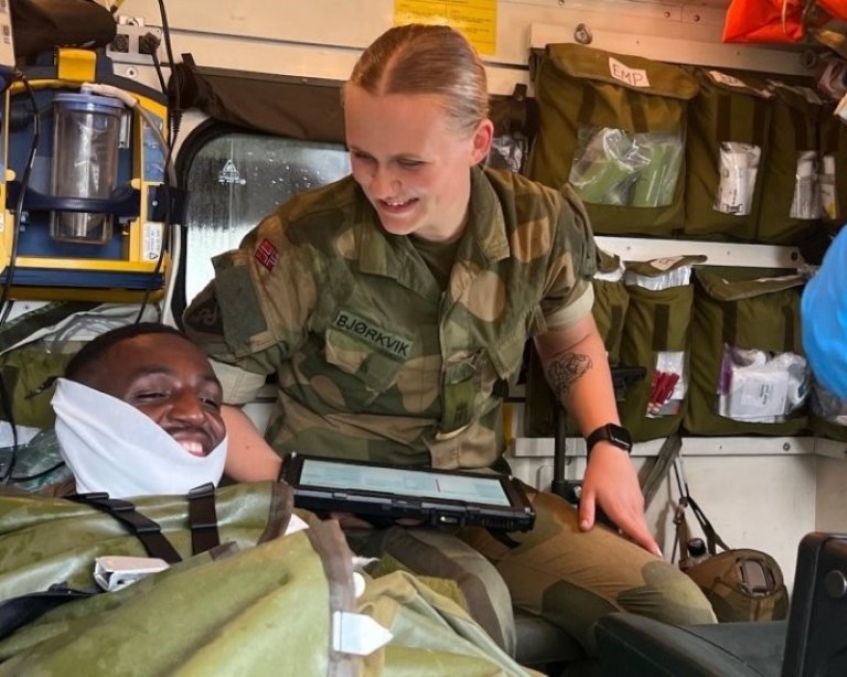 Soldat med nettbrett smiler ned mot pasient