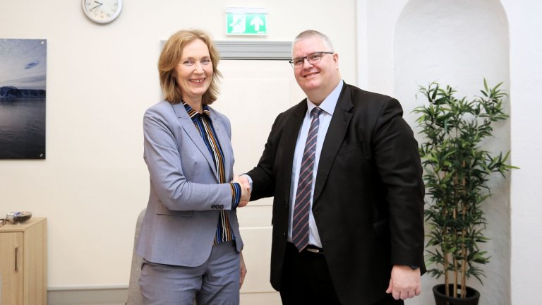 Smilende mann og kvinne gir hverandre et håndtrykk