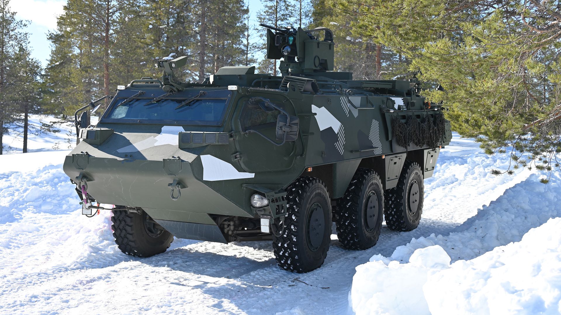 Pansret militærkjøretøy på en snødekt vei.