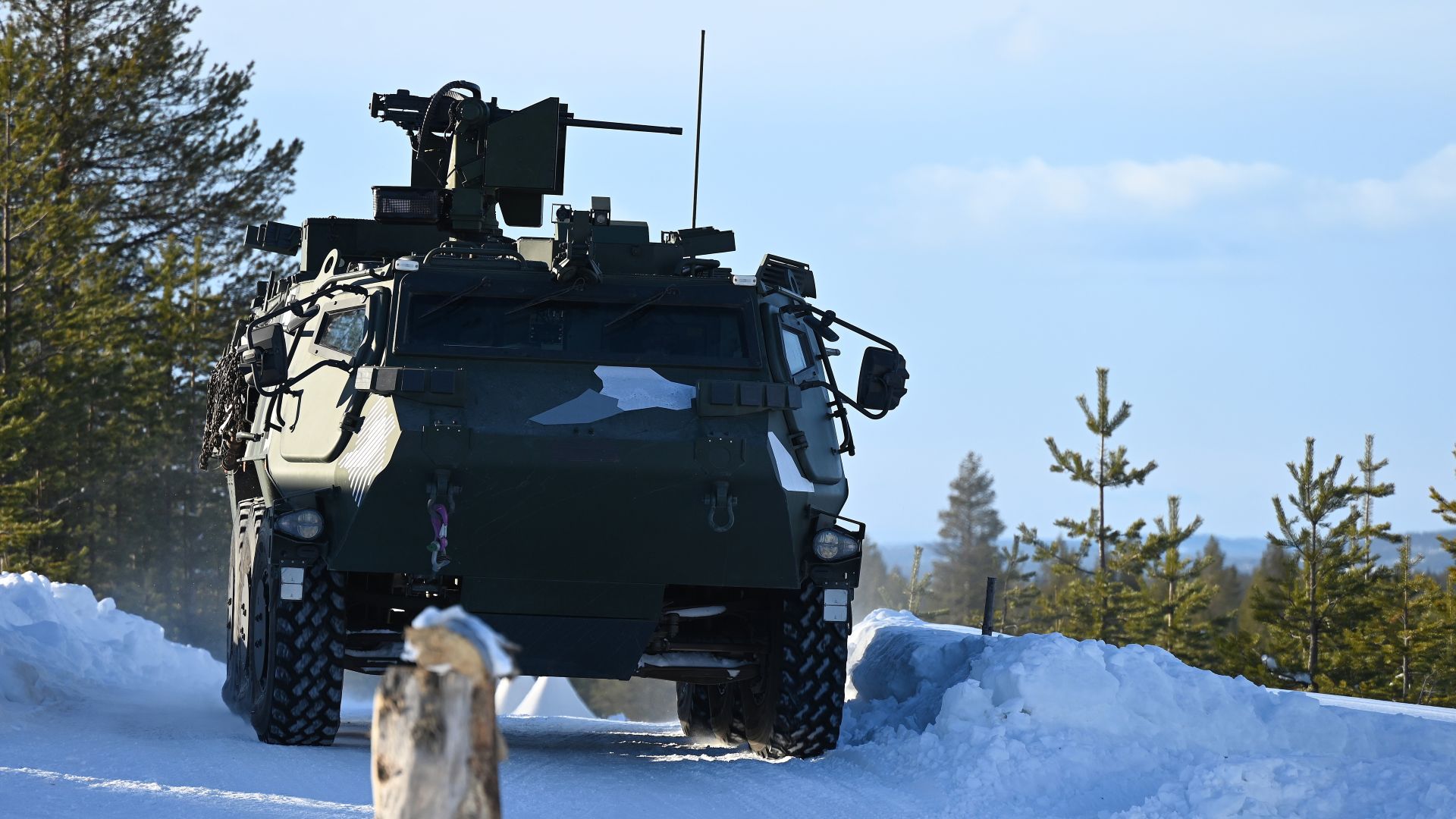 Pansret militærkjøretøy på en snødekt vei.