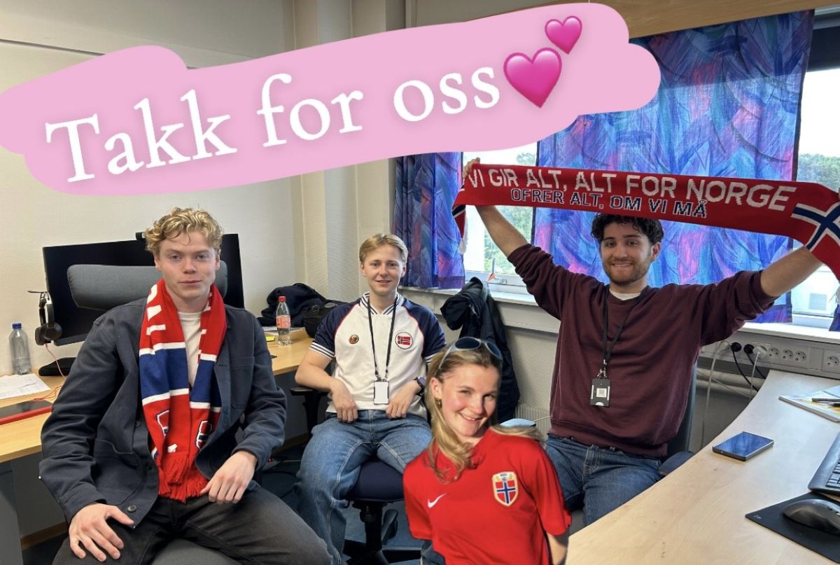 Fire personer med norske supporterklær  på et kontor