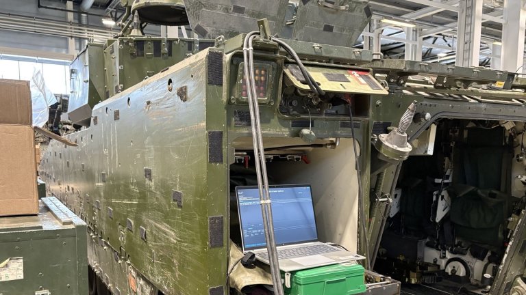 Militært kjøretøy i verksted med bærbar PC tilkoblet teknisk utstyr.