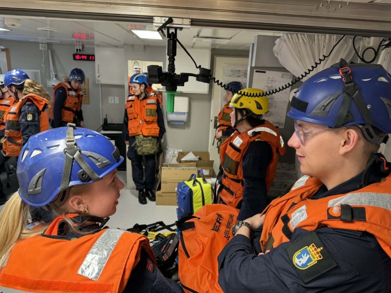 Forpleiningspersonell har gjort seg klar til rullemønstring i helikopterhangar. Rullemønstring arrangeres når hele besetningen har mønstret på i nytt tokt. Alt utstyr tas på, og materiellet skal vises fram.  
