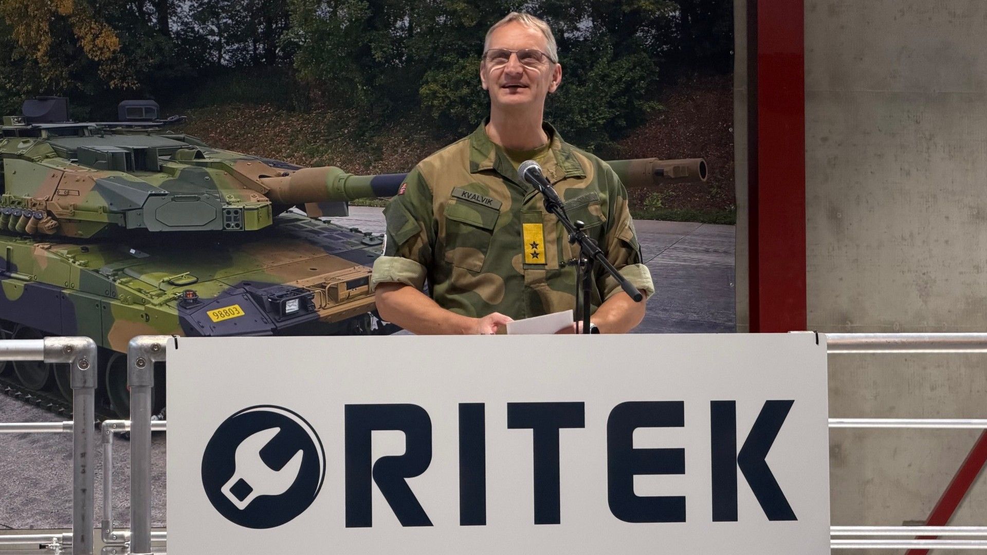 Mann i militæruniform holder tale på pdium
