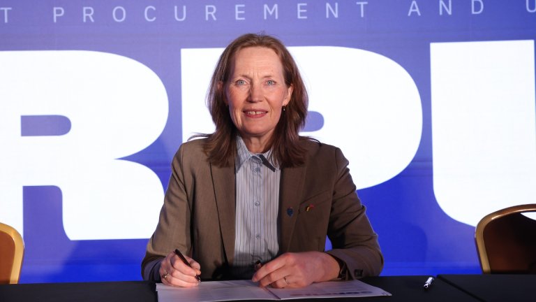 Smilende kvinne signerer dokumenter