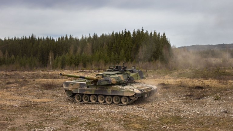 Stridsvogn kjører med skog i bakgrunnen