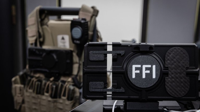 Telefonholder med FFI printet på, med en stridsvest i bakkant