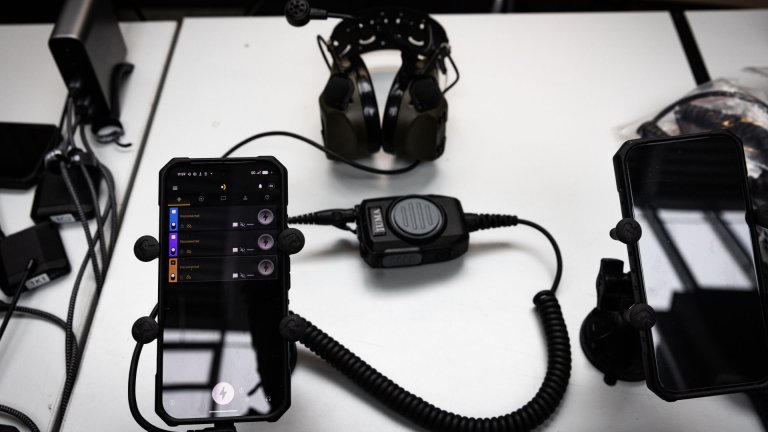 Mobiltelefon koblet til kommunikasjonsutstyr med headset og kontrollenhet på bord.