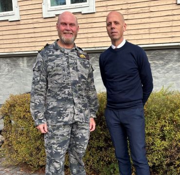 Kommandørkaptein og forsvarsliaison Darren McDevitt og seksjonssjef for Internasjonalt Programkontor i Forsvarsmateriell Stian Bendiksen, foran Forsvarsmateriells hovedkontor. Foto: Forsvarsmateriell