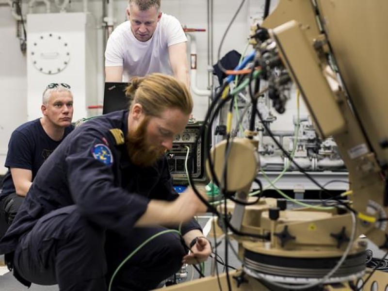 Vidar Madsen (til venstre), Hans Olav Molden og Erik Wangel Alsaker (foran) tester oppkobling av antennen i hangaren på KV «Svalbard». 